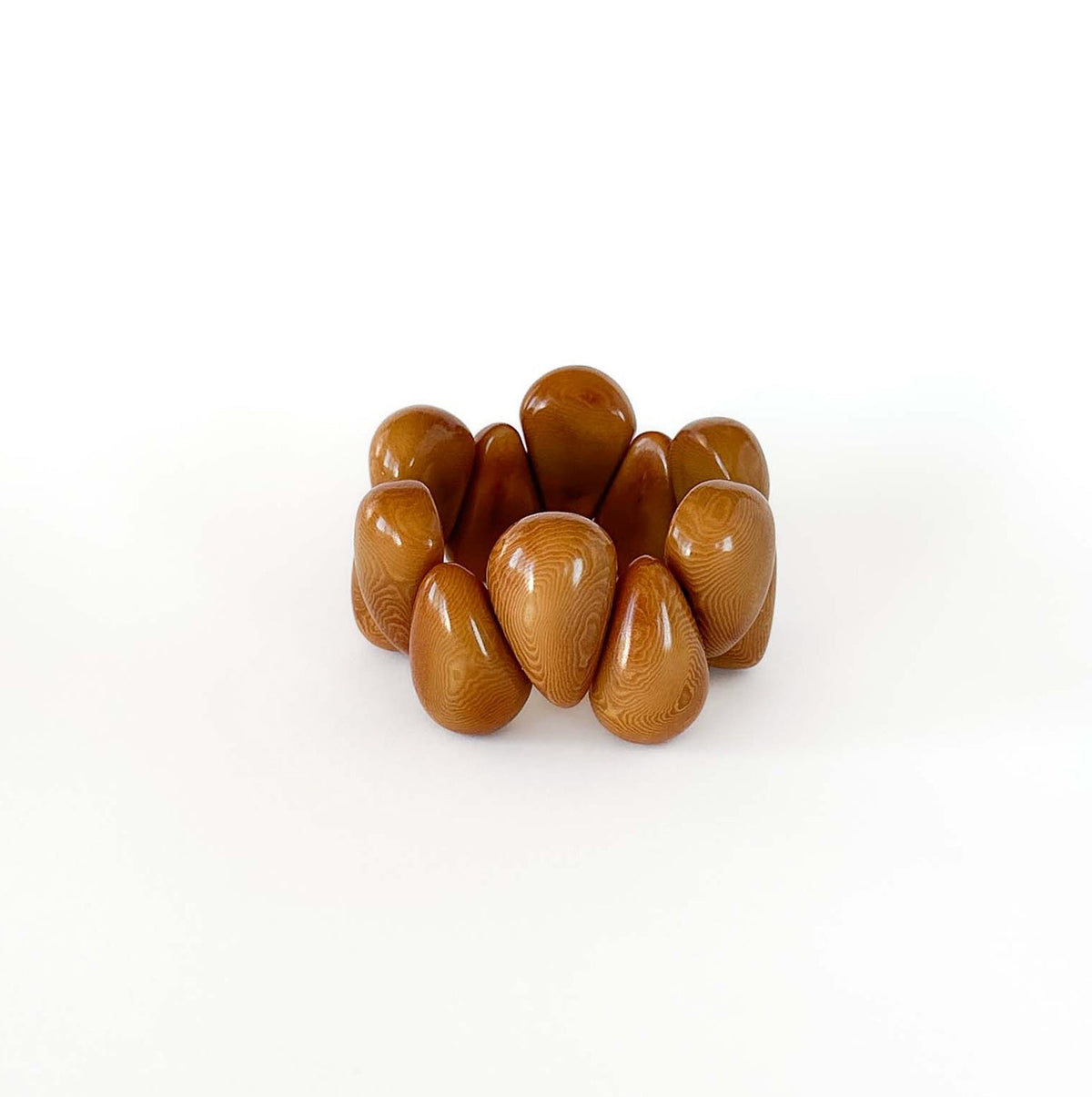 A cluster of glossy, teardrop-shaped brown tagua beads arranged on a seamless white background.