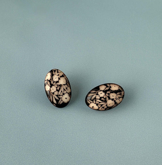 Pair of earrings with a decorative engraved design on a ivory surface