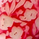 Two red earrings of tagua nuts, engraved with a floral pattern.