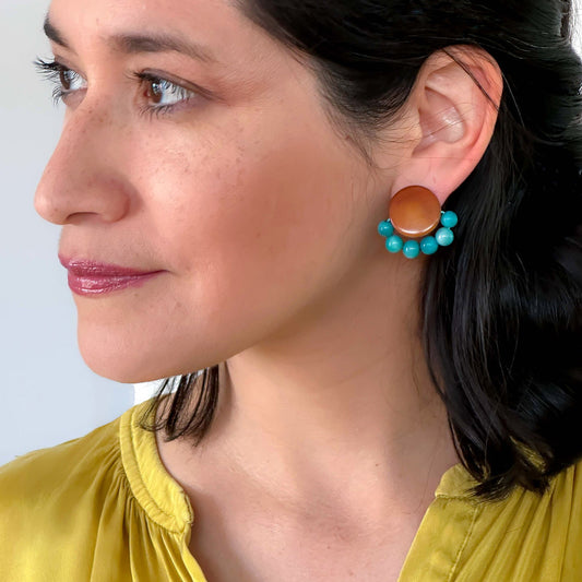 Woman wearing a yellow top with turquoise and brown earrings made with spherical tagua nut beads