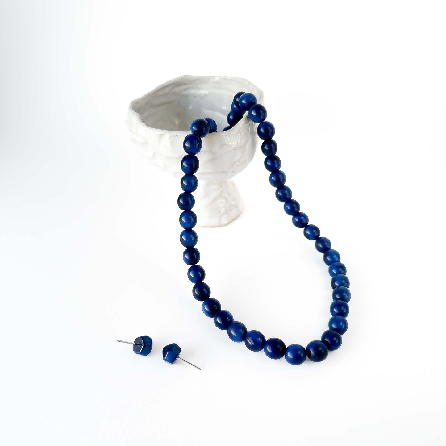 Blue beaded tagua necklace and earrings on a white background