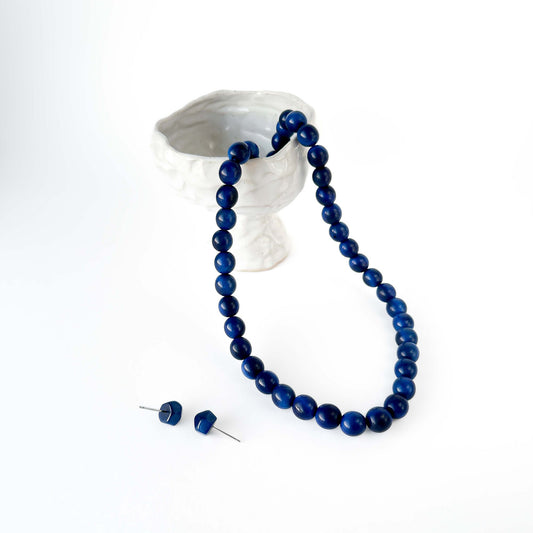 Blue beaded tagua necklace and earrings on a white background