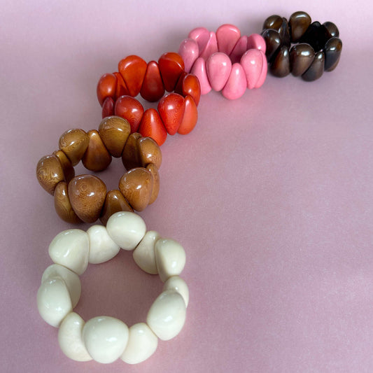 Set of colorful beaded bracelets on a pink background. Modern organic design bracelets, made of sustainable tagua nut / vegetable ivory