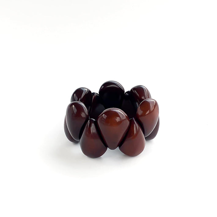 A dark brown beaded stretch tagua bracelet with smooth, glossy teardrop-shaped beads, photographed on a clean white background.
