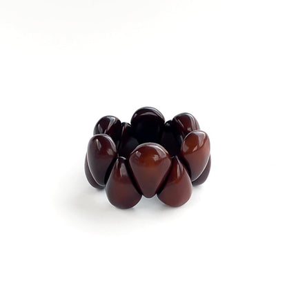 A dark brown beaded stretch tagua bracelet with smooth, glossy teardrop-shaped beads, photographed on a clean white background.