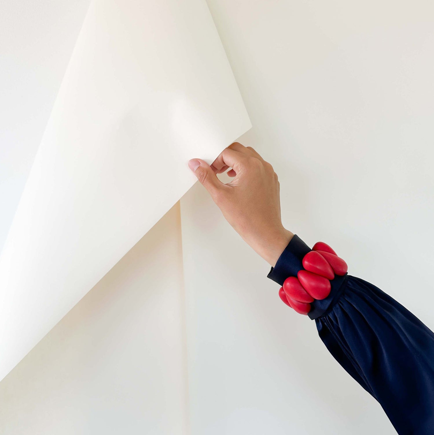 Person peeling back a large white sheet wearing a design bracelet, made of sustainable tagua nut / vegetable ivory