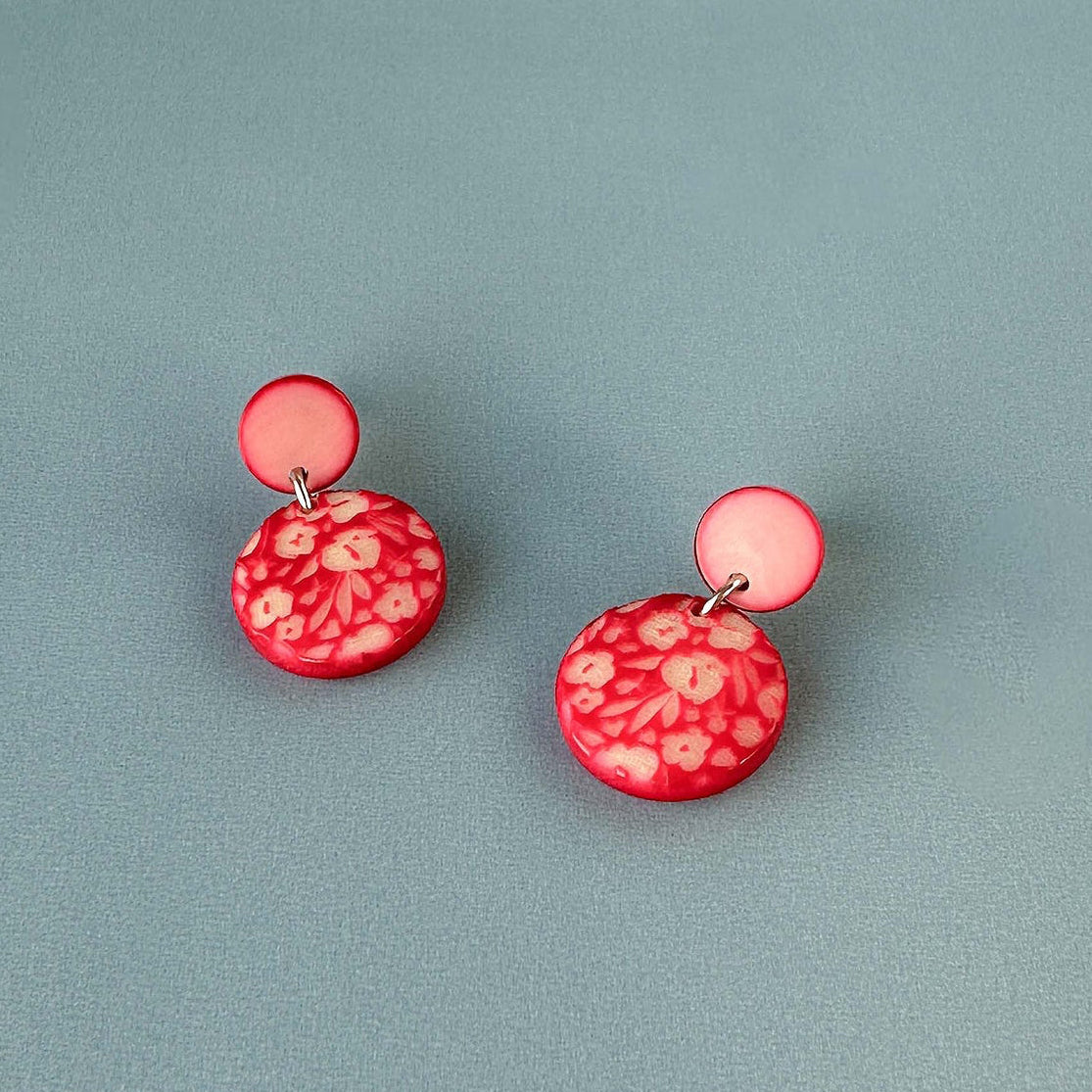 Pair of earrings with a decorative engraved design on a ivory surface