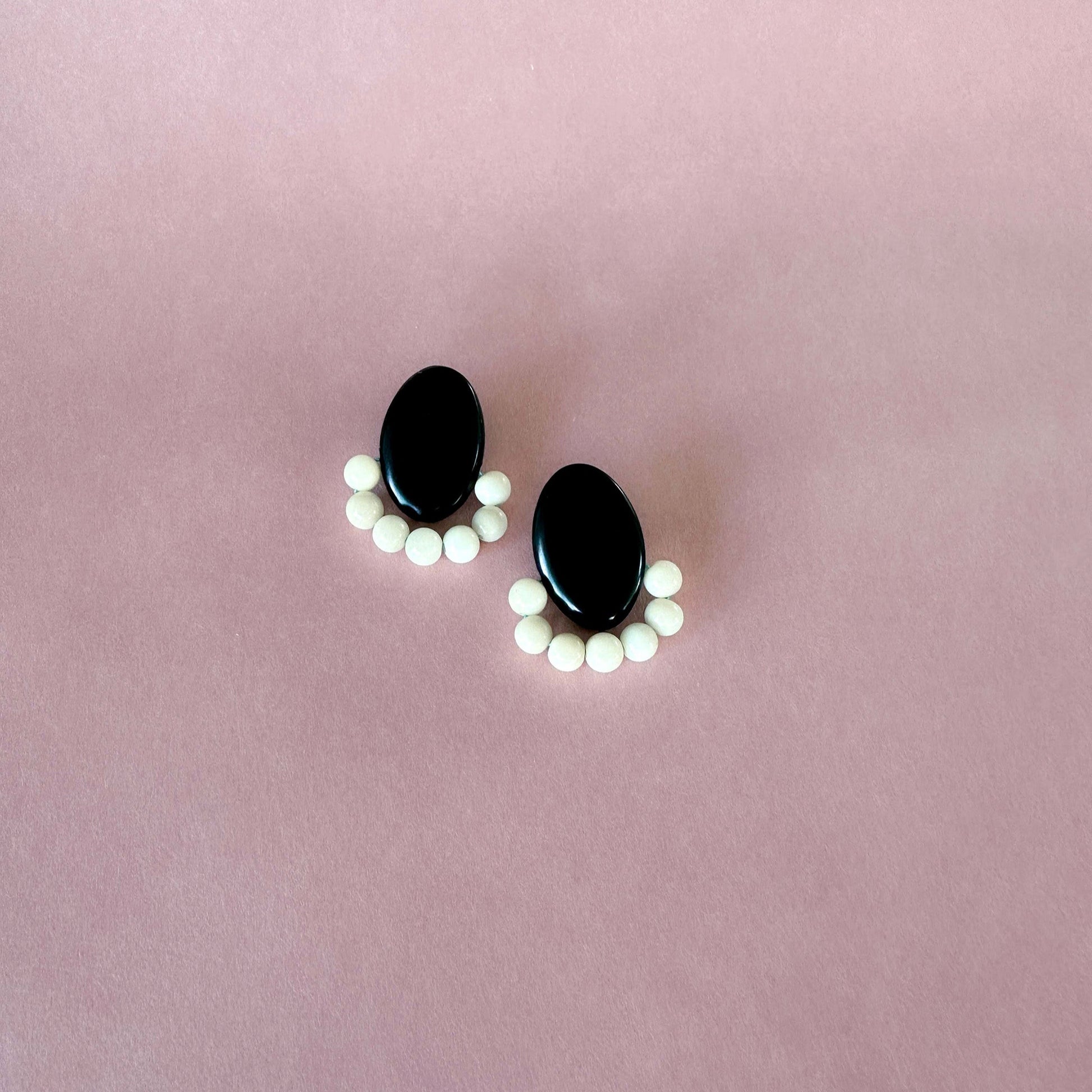 Black and white beaded earrings on a pink background. Handmade with tagua nut beads and natural dyes.