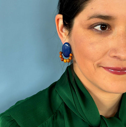 Woman wearing electric blue earrings with brown beads, handmade with tagua nut beads and natural dyes.