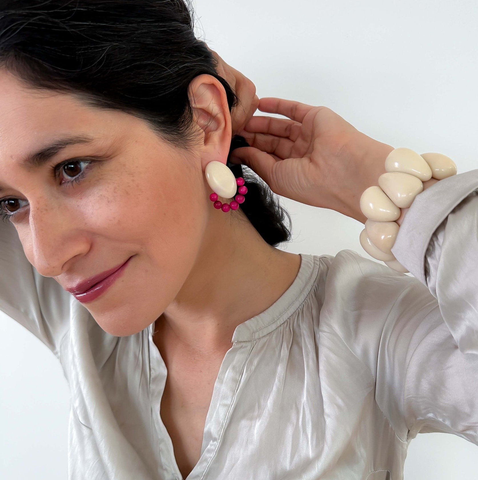 Woman wearing earrings and ivory bracelet, handmade with tagua nut beads and natural dyes.

