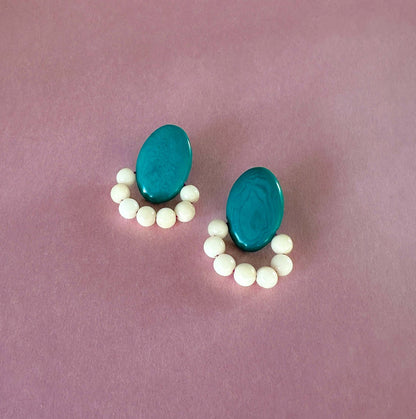 Teal earrings handmade with tagua nut beads and natural dyes on a pink background