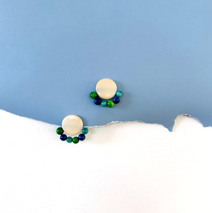 Pair of round earrings with colorful beads on a blue and white gradient background