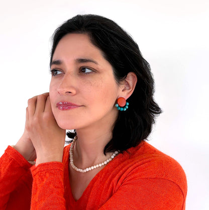 Woman wearing a pair of tagua nut earrings with spherical beads and a tagua nut necklace in its ivory tone