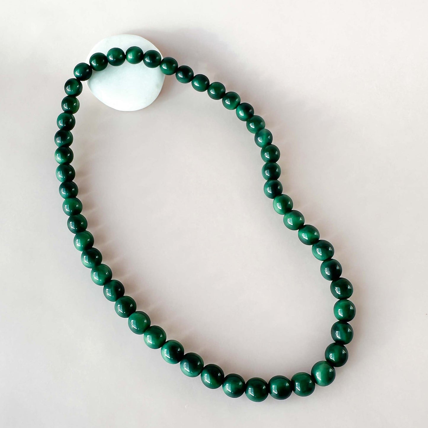 Green beaded necklace on a light gray background