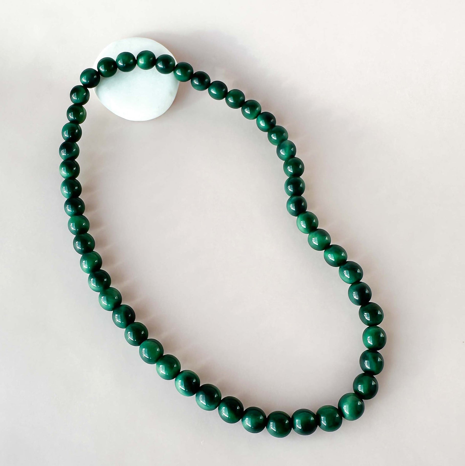 Green beaded necklace on a light gray background