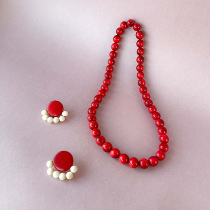 Red beaded tagua nut necklace and earrings on a light gray background