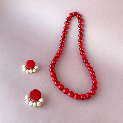 Red beaded necklace and earrings on a light gray background
