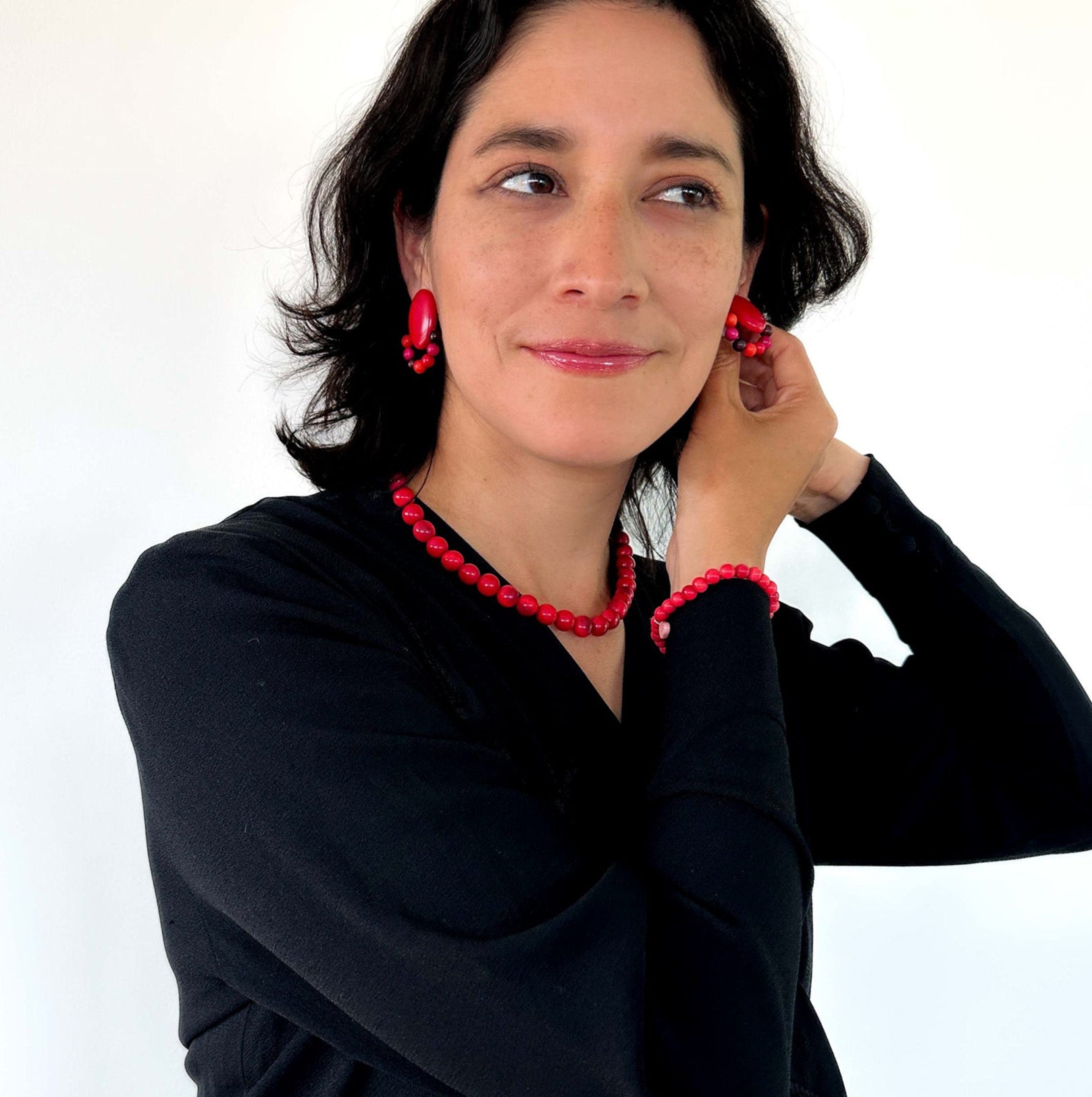 Red tagua nut beads necklace, bracelet and earrings on model.