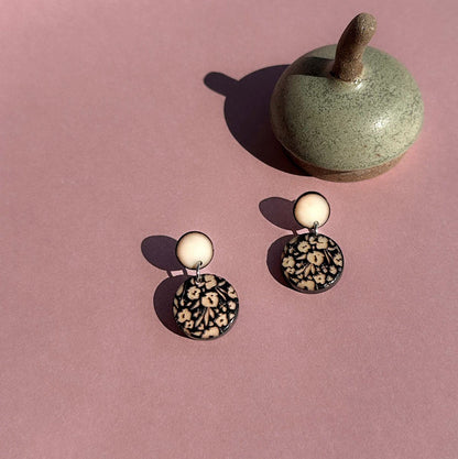 Pair of earrings with a decorative engraved design on a ivory surface